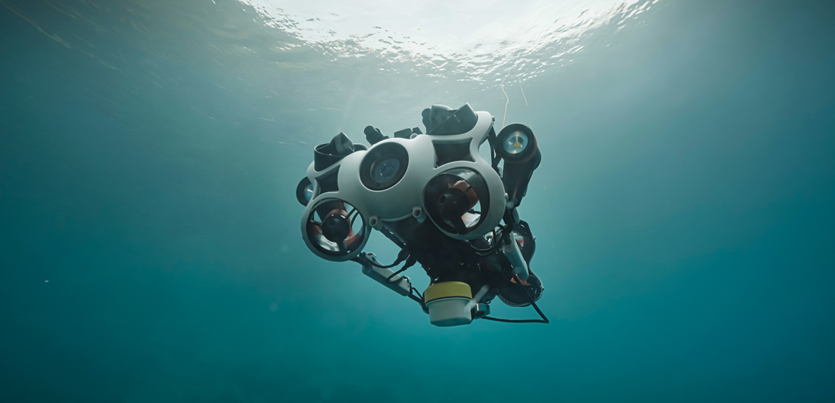 Unterwasser-Roboter mit Kameralinse und Propellern schwimmt im klaren Wasser nahe der Oberfläche.